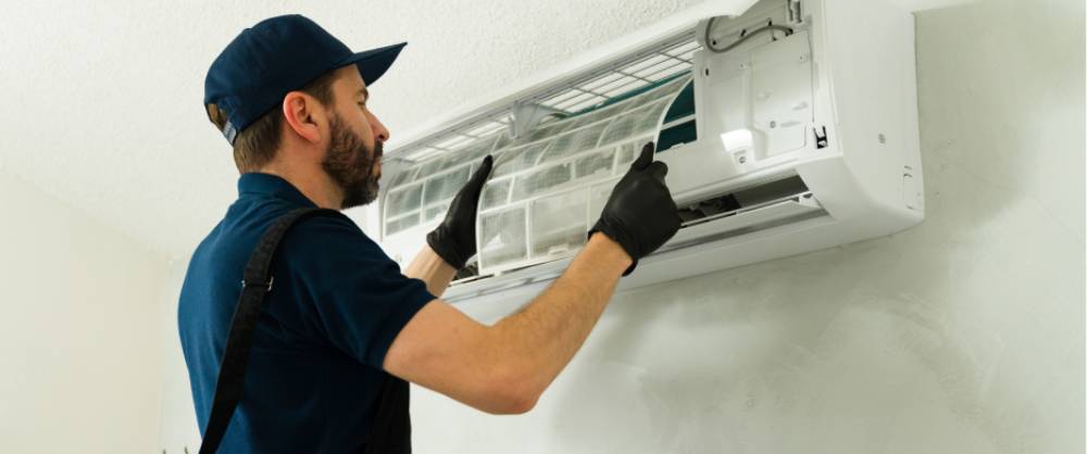 Air conditioning technician performing maintenance on a split-type AC filter
